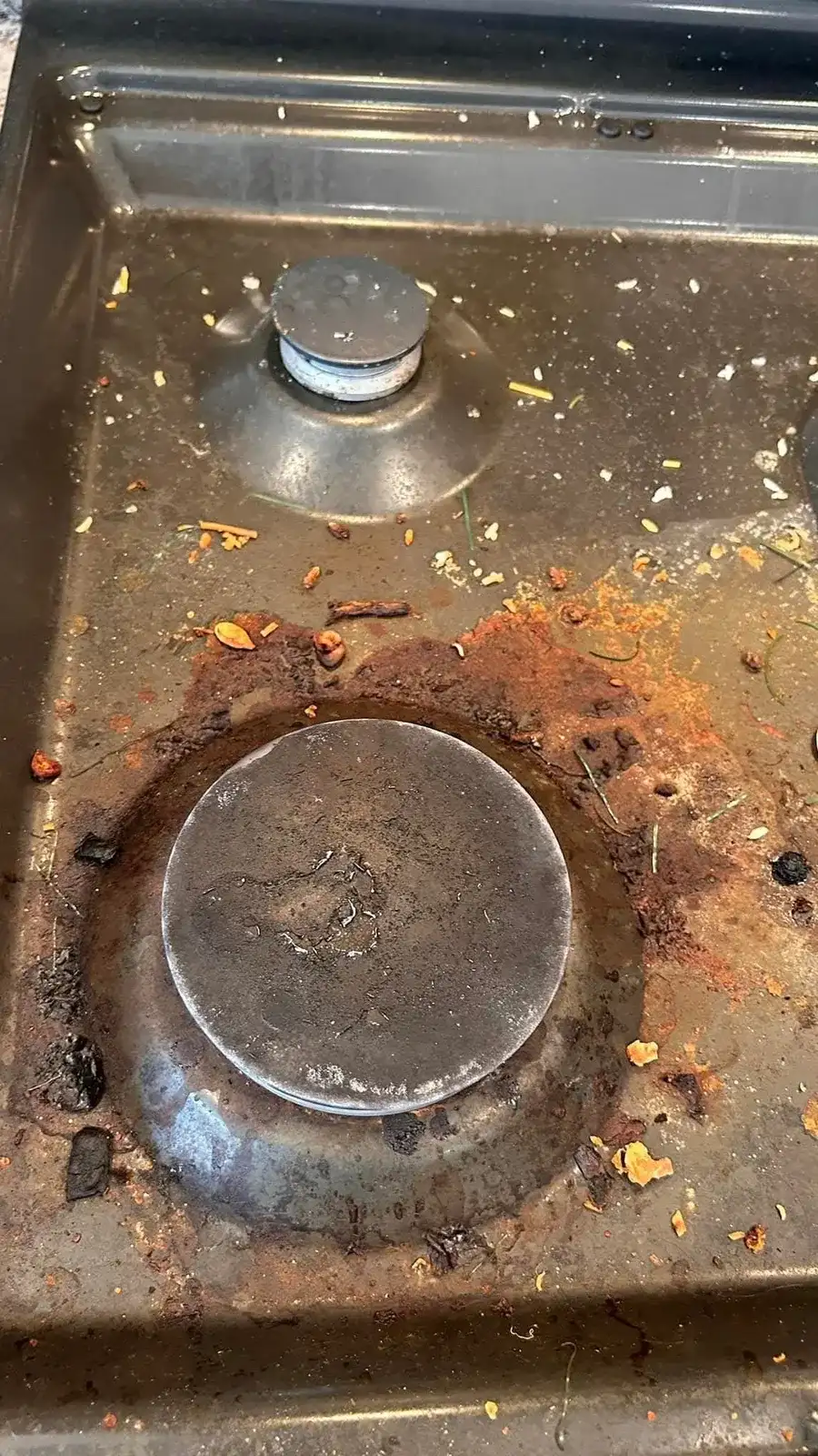 Before: stainless gas cooktop burner crusted with rust-colored burnt food