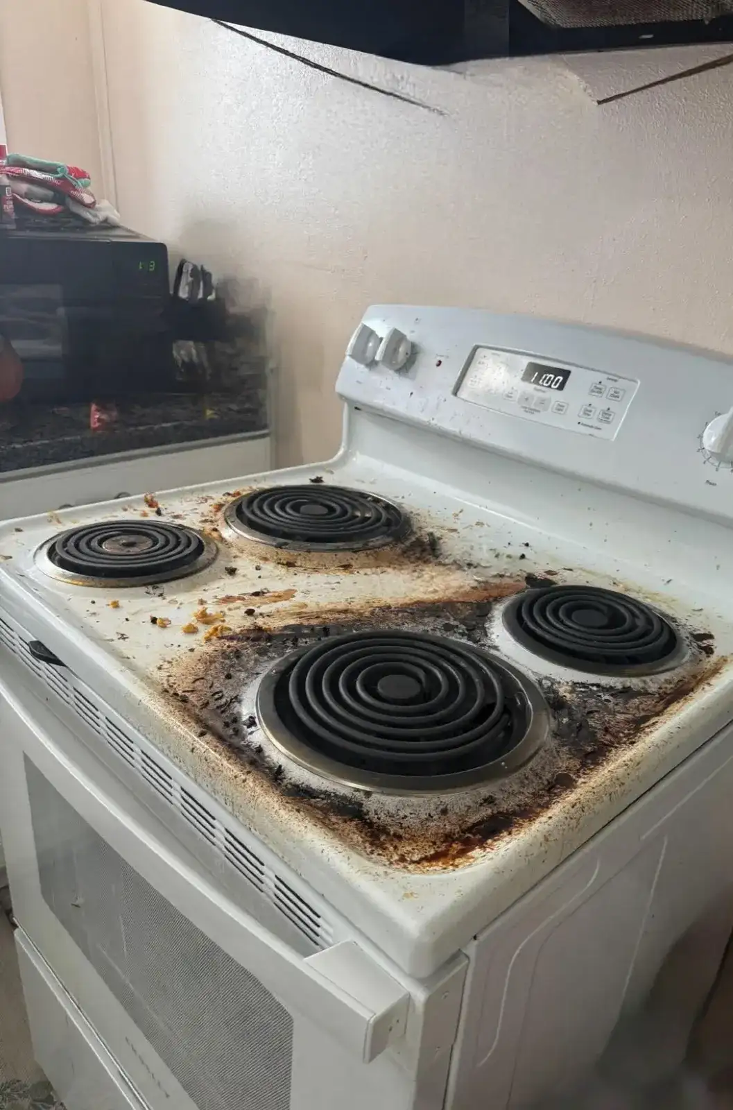 Before: white electric stove with burnt-on grease around every coil burner