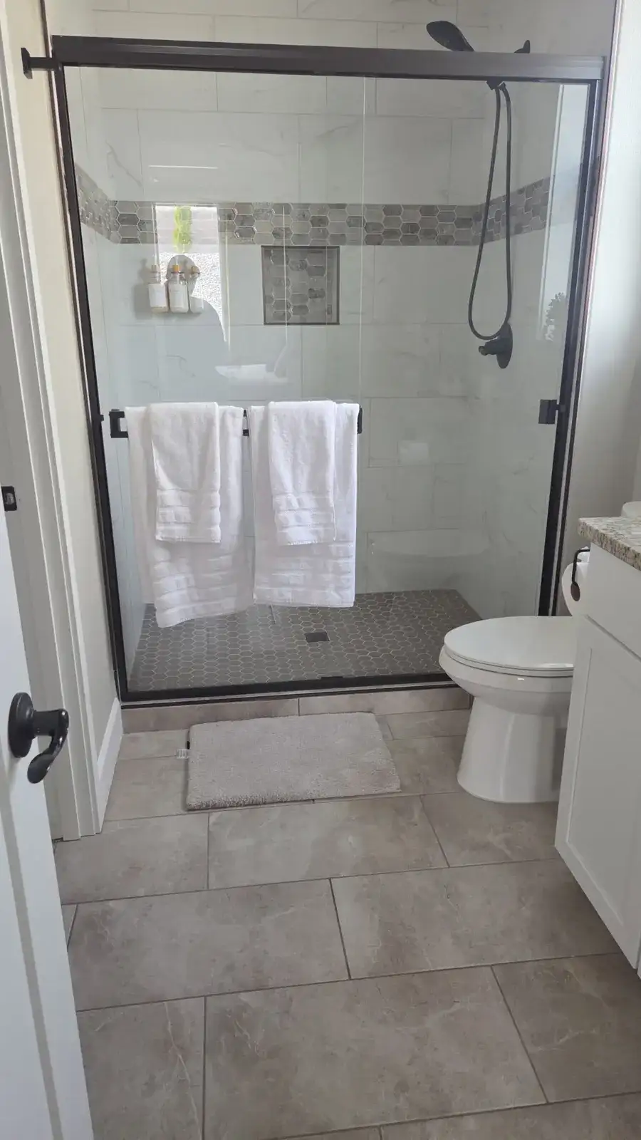 Spotless walk-in shower with clear glass doors and folded white towels
