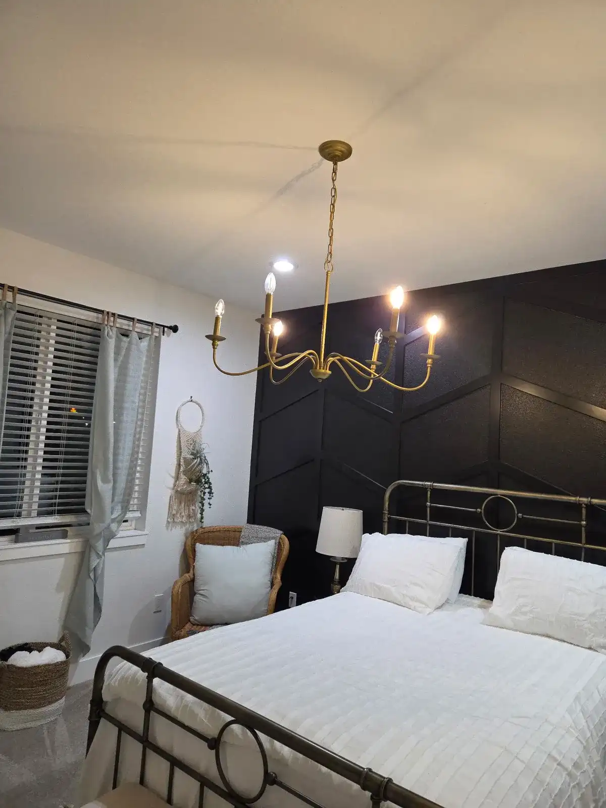Tidy bedroom with a made bed, fresh white bedding and a gold chandelier