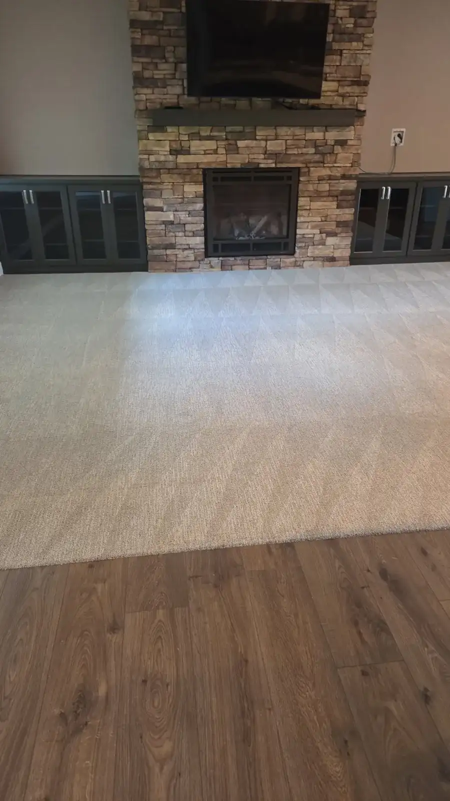 Empty living room with fresh lines in the carpet and a stone fireplace