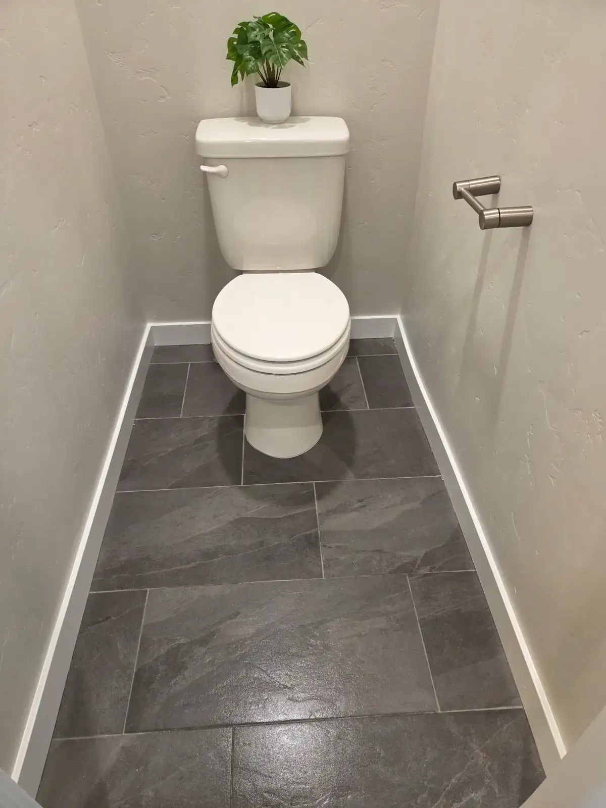 Small half bath with a clean toilet and freshly mopped tile floor