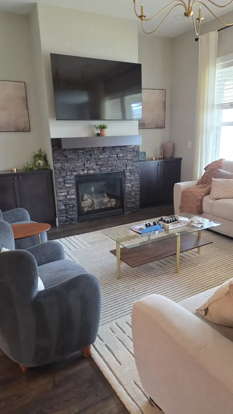 Bright living room after a cleaning, with a stone fireplace, soft chairs and a glass coffee table