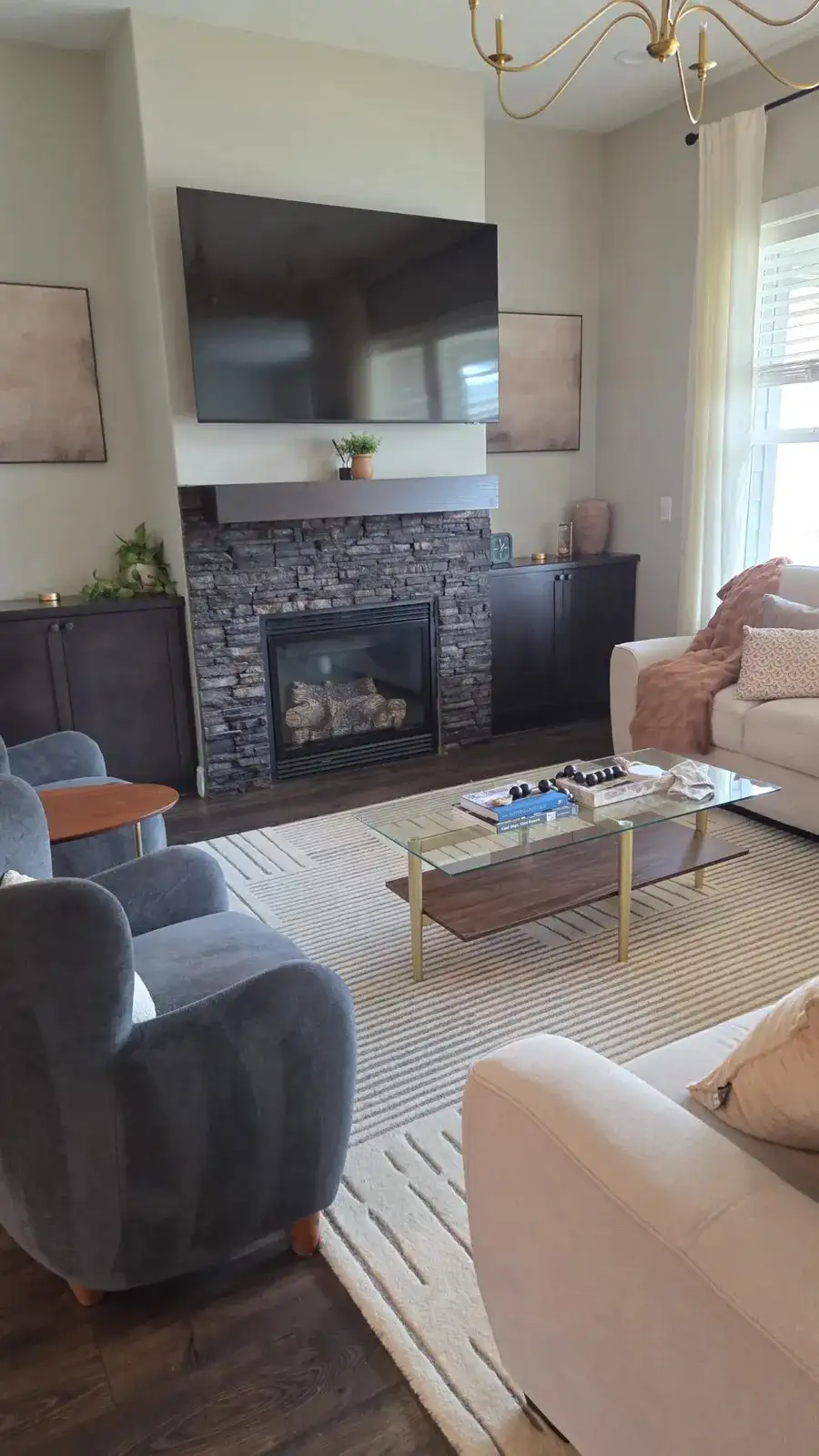Bright living room after a cleaning, with a stone fireplace, soft chairs and a glass coffee table