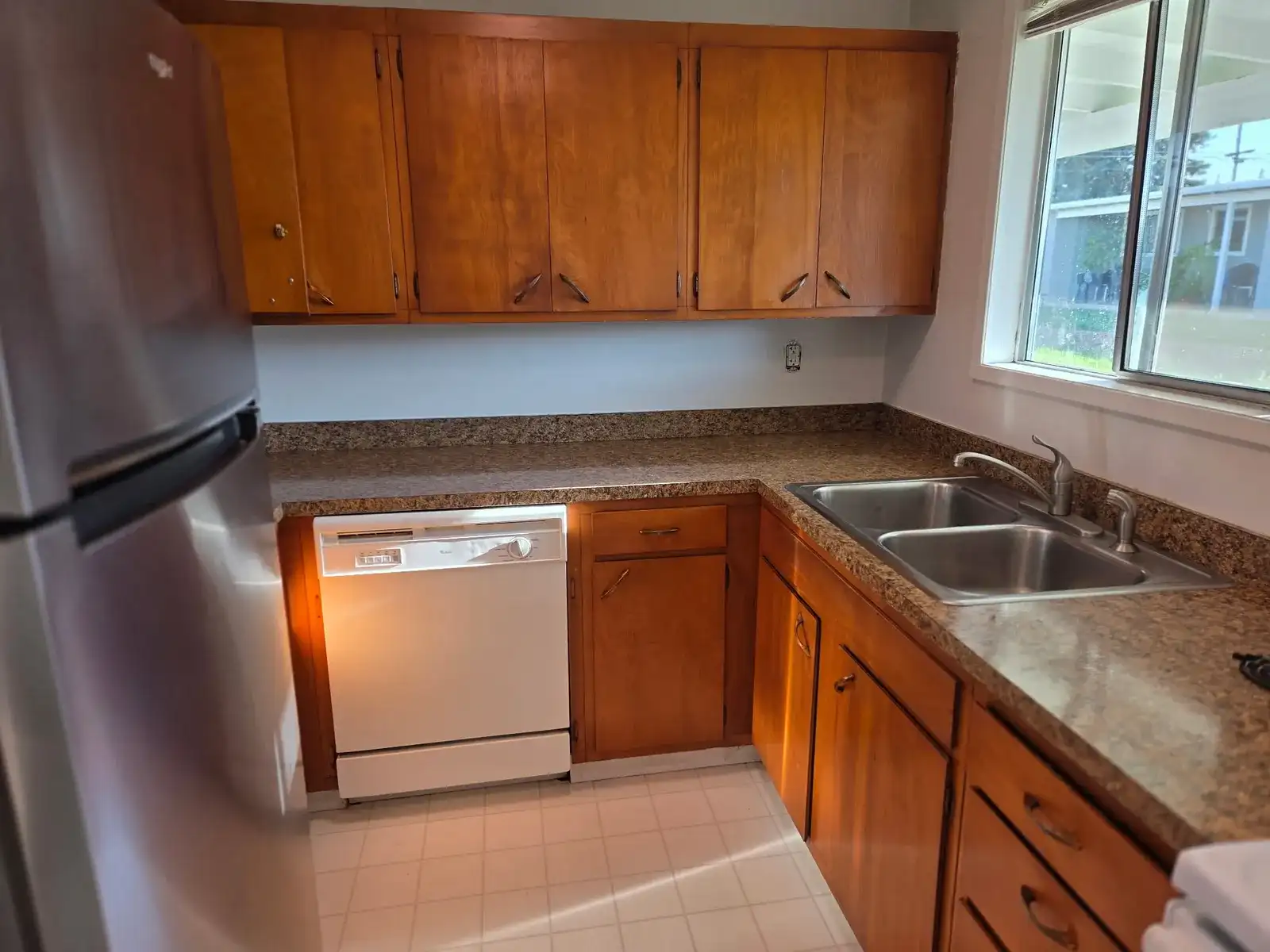 Empty kitchen after a move-out cleaning, with wood cabinets, granite counters and a clean tile floor
