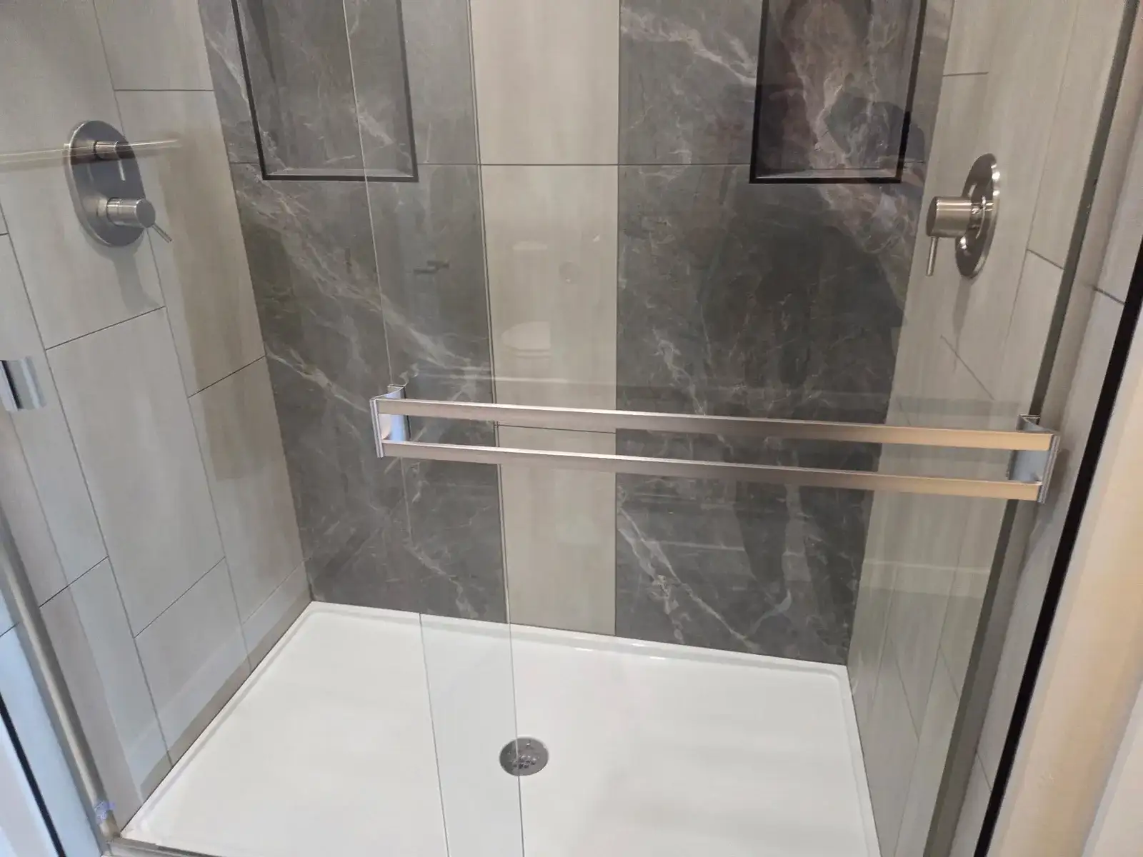 Empty shower scrubbed clean, with a bright white floor and clear glass