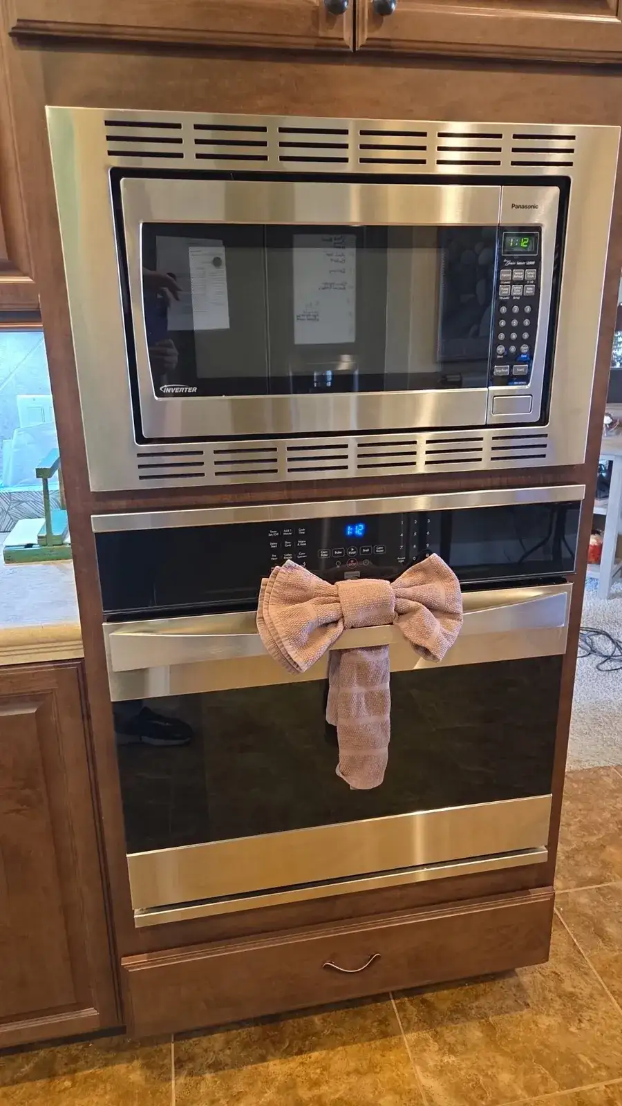 Shiny wall oven and microwave with a towel tied in a bow on the oven door